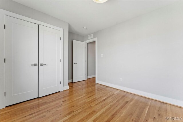 unfurnished bedroom featuring light wood finished floors, visible vents, baseboards, and a closet