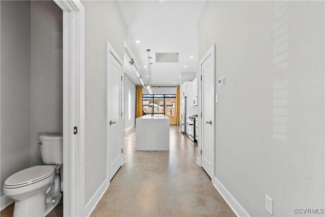 hallway featuring recessed lighting, finished concrete flooring, and baseboards