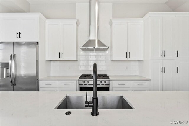 kitchen with stainless steel appliances, white cabinetry, backsplash, and wall chimney exhaust hood