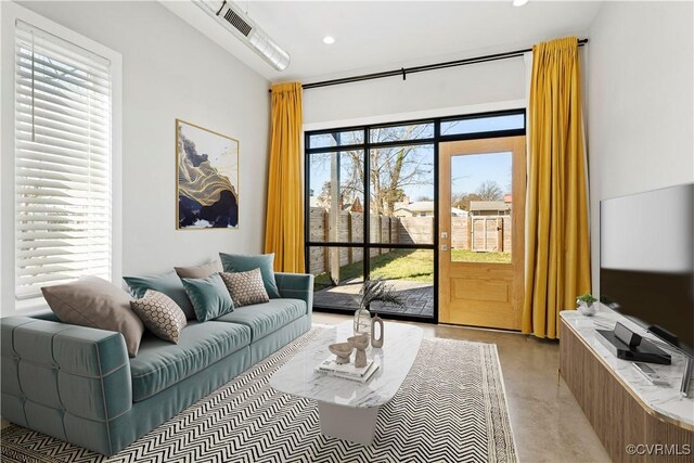 living area featuring finished concrete flooring, visible vents, and recessed lighting