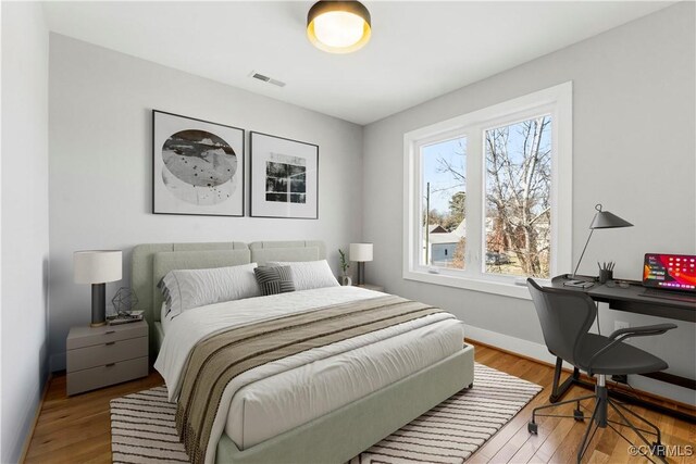 bedroom featuring baseboards, visible vents, and light wood-style floors