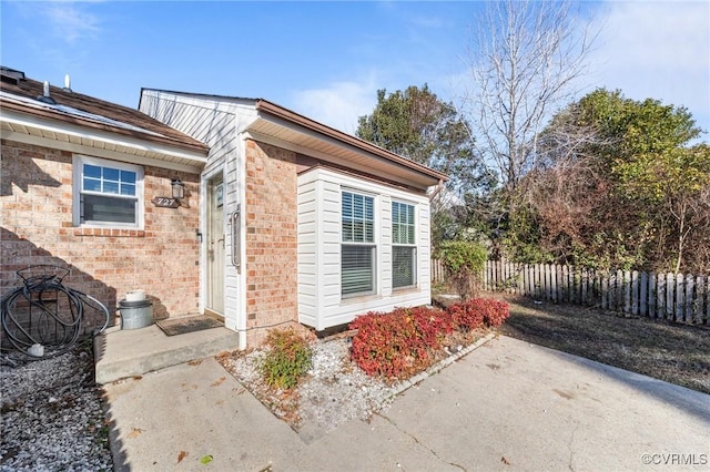 property entrance with brick siding, a patio area, and fence