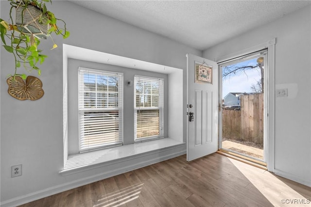 foyer entrance with a textured ceiling and wood finished floors