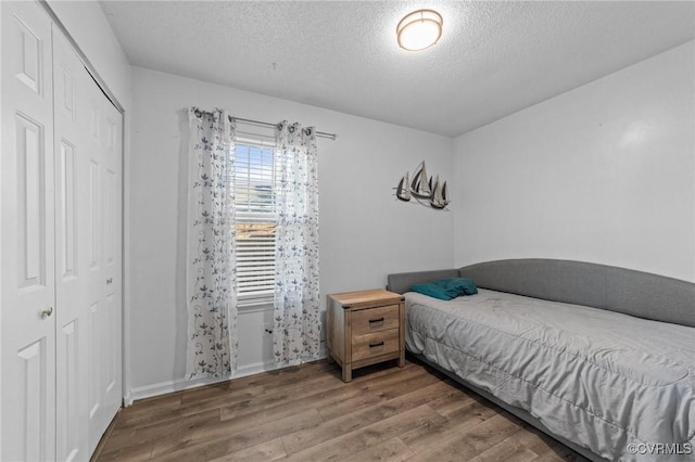 bedroom featuring a textured ceiling, a closet, and wood finished floors