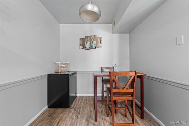 dining space featuring a wainscoted wall and wood finished floors