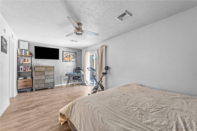 bedroom with ceiling fan, a textured ceiling, wood finished floors, and visible vents