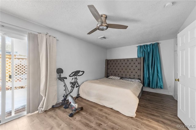 bedroom featuring access to exterior, a textured ceiling, a ceiling fan, and wood finished floors