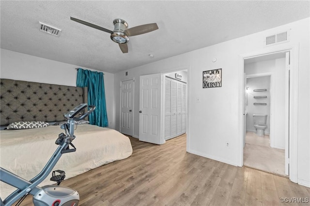 bedroom featuring a ceiling fan, a textured ceiling, visible vents, and wood finished floors