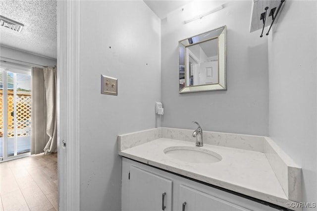 bathroom with visible vents, wood finished floors, a textured ceiling, and vanity