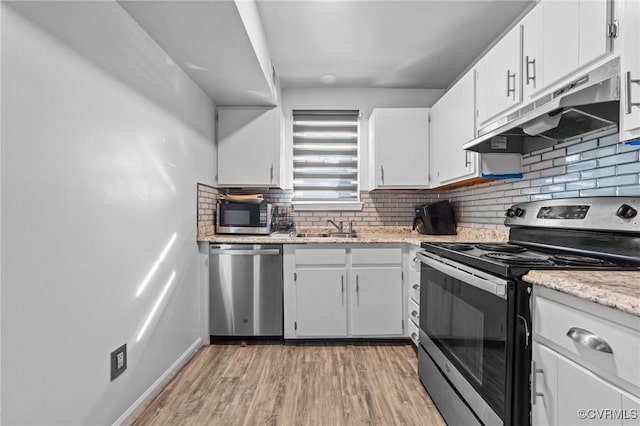 kitchen with white cabinets, appliances with stainless steel finishes, a sink, under cabinet range hood, and backsplash