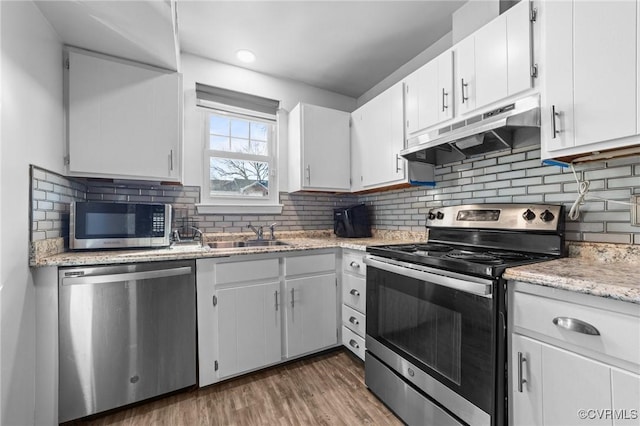 kitchen with dark wood-style floors, stainless steel appliances, white cabinetry, a sink, and under cabinet range hood