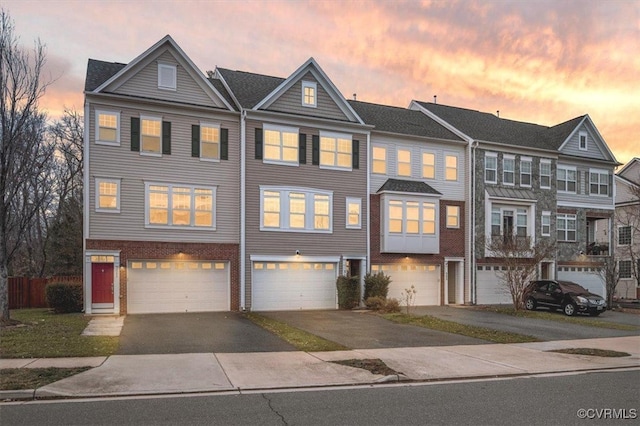 townhome / multi-family property featuring brick siding, a garage, and driveway