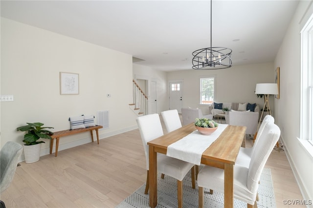 dining room with light wood-type flooring, visible vents, stairway, and baseboards