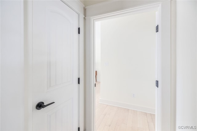 corridor with light wood-style flooring and baseboards