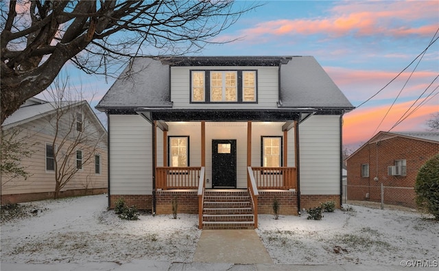 bungalow-style home with covered porch, a shingled roof, and fence