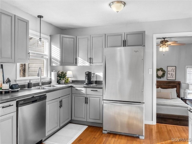 kitchen with appliances with stainless steel finishes, dark countertops, a sink, and gray cabinetry