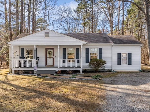 view of front of house with driveway, covered porch, a shingled roof, and a front lawn