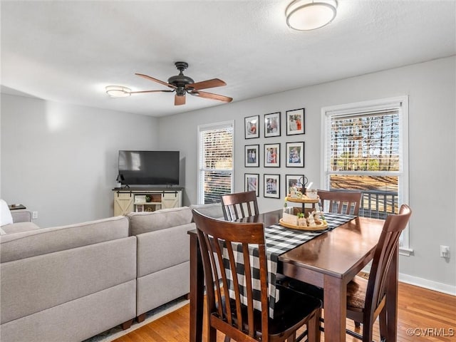 dining space featuring baseboards, ceiling fan, and light wood finished floors