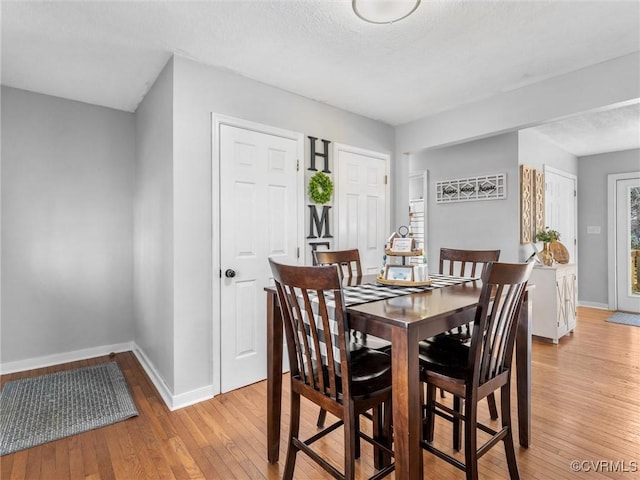 dining area featuring light wood-type flooring and baseboards