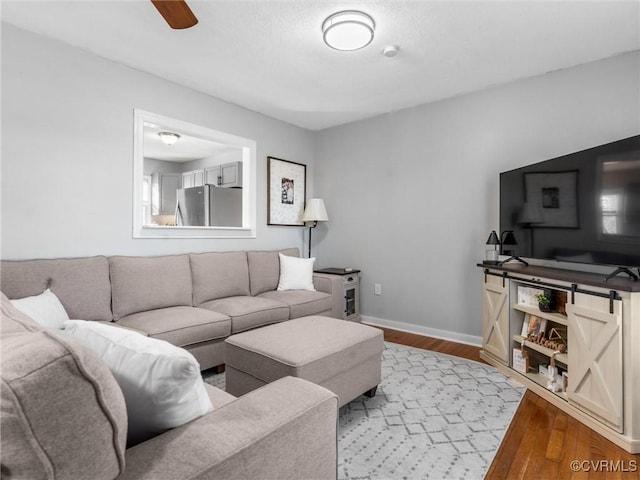 living room featuring ceiling fan, wood finished floors, and baseboards