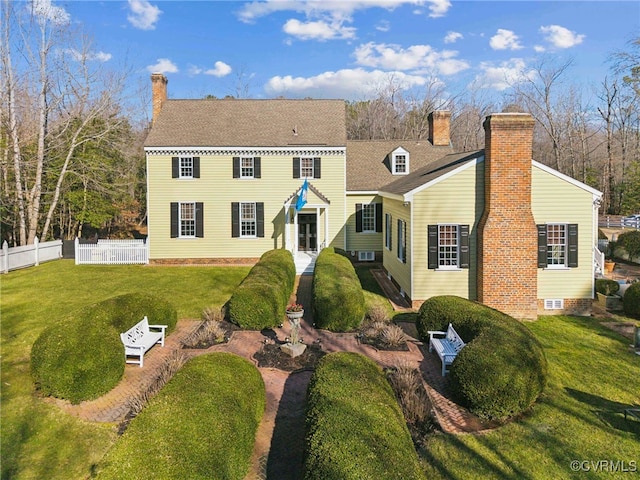 view of front of home featuring fence, a chimney, and a front lawn