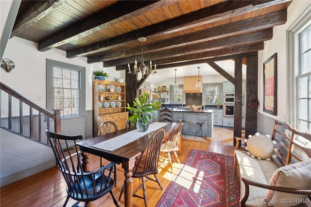 dining area with a chandelier, light wood-type flooring, plenty of natural light, and stairway