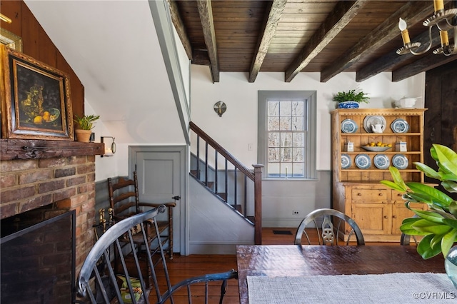 interior space featuring wooden ceiling, stairs, a brick fireplace, beam ceiling, and dark wood finished floors