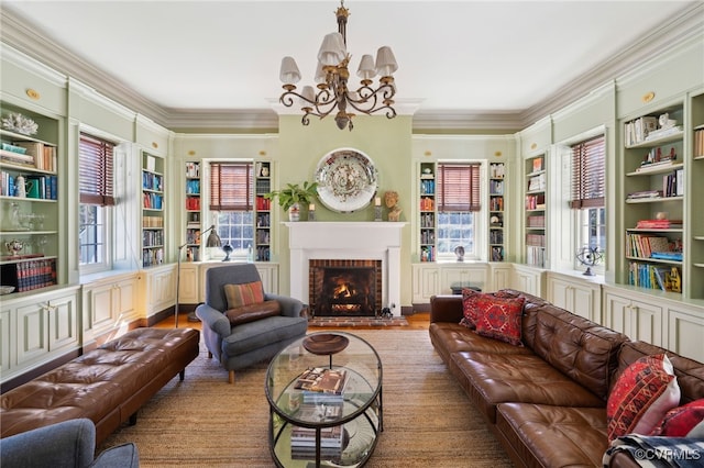 living area with built in shelves, a fireplace, crown molding, and an inviting chandelier