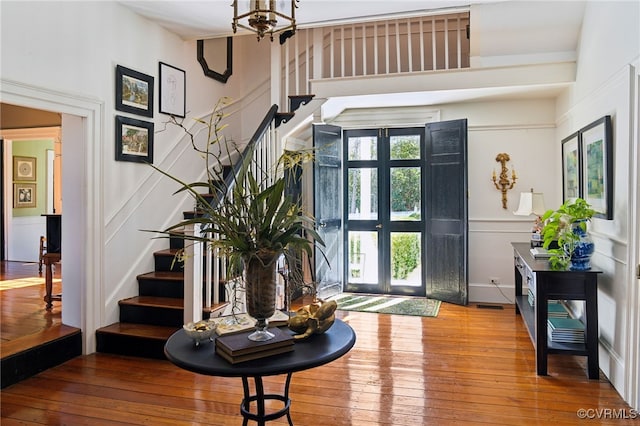 entryway with french doors, stairway, wood finished floors, and a notable chandelier