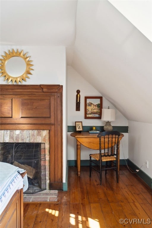 office with dark wood-style floors, a fireplace, baseboards, and vaulted ceiling