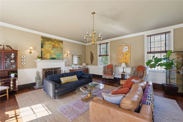 living room featuring dark wood-type flooring, a chandelier, crown molding, and a fireplace