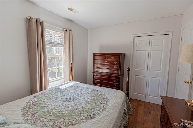 bedroom with visible vents, wood finished floors, and a closet