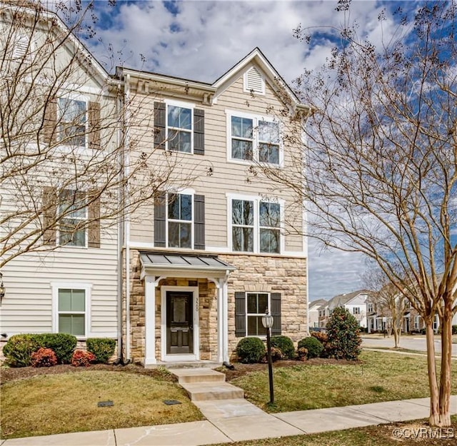 multi unit property with stone siding and a front yard