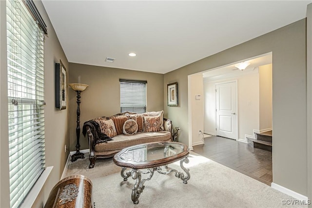 living area featuring baseboards, stairs, visible vents, and wood finished floors