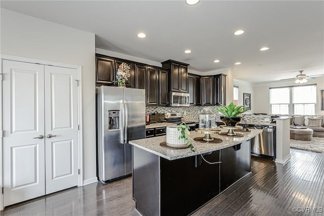 kitchen with a center island, a breakfast bar area, stainless steel appliances, tasteful backsplash, and open floor plan