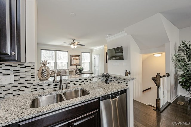 kitchen with light stone counters, a sink, stainless steel dishwasher, dark wood-style floors, and tasteful backsplash