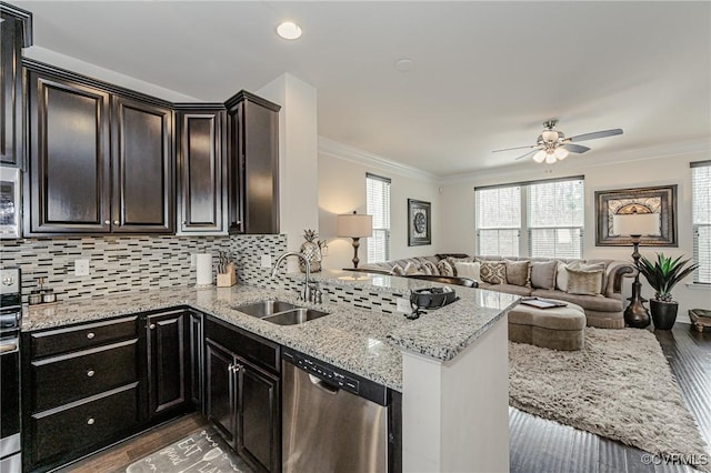 kitchen with crown molding, backsplash, open floor plan, a sink, and dishwasher