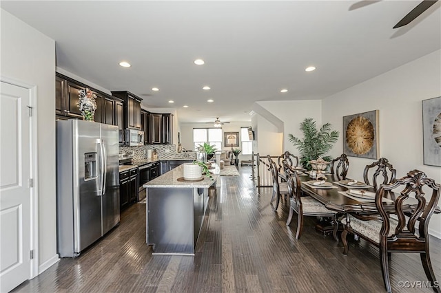 kitchen featuring ceiling fan, appliances with stainless steel finishes, backsplash, a center island, and dark wood finished floors