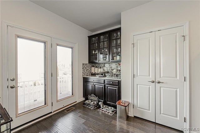 bar featuring dark wood-style floors, a dry bar, visible vents, and decorative backsplash