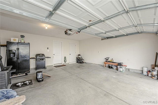 garage featuring a garage door opener and black fridge with ice dispenser