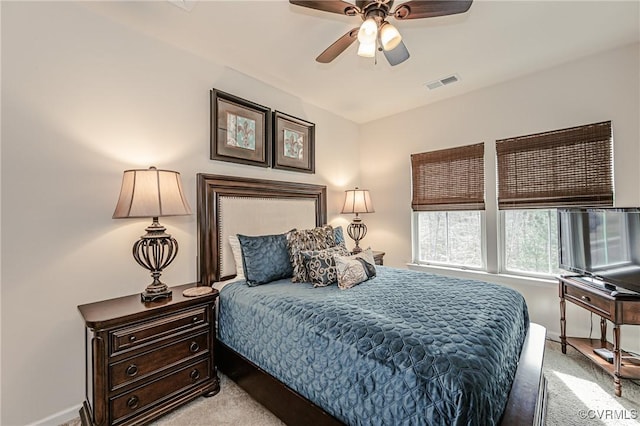 bedroom featuring a ceiling fan, visible vents, and light carpet