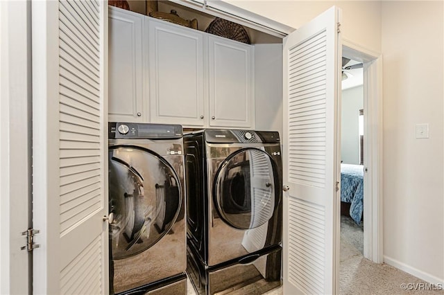 clothes washing area featuring light carpet, cabinet space, washer and clothes dryer, and baseboards