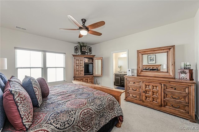 bedroom featuring visible vents, ensuite bathroom, a ceiling fan, and light colored carpet