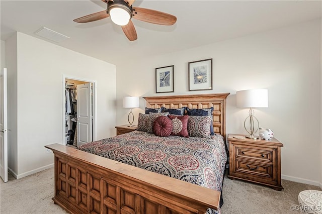 bedroom featuring light carpet, a spacious closet, and baseboards