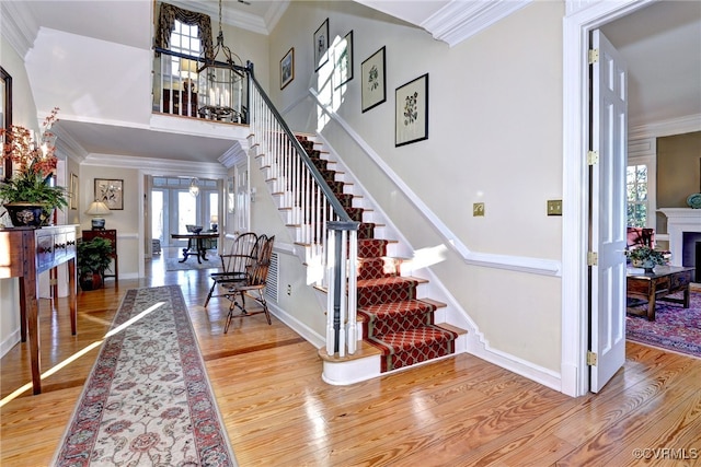 entryway with crown molding, stairs, a fireplace, and wood finished floors