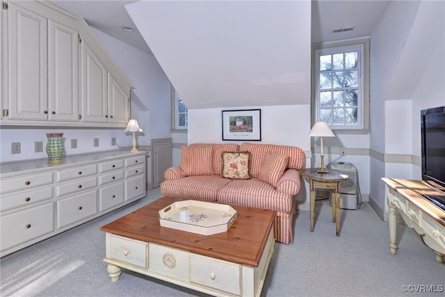 living area with light colored carpet, visible vents, lofted ceiling, and baseboards