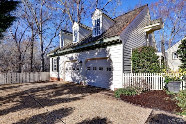 view of property exterior featuring a garage, fence, and driveway