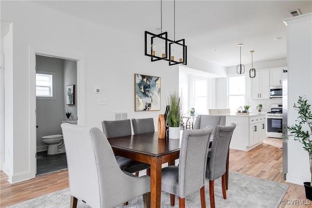 dining room with light wood finished floors, visible vents, and baseboards