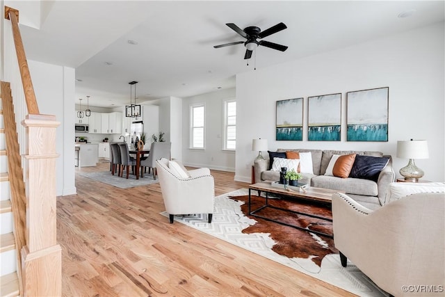 living room with ceiling fan, light wood finished floors, and baseboards