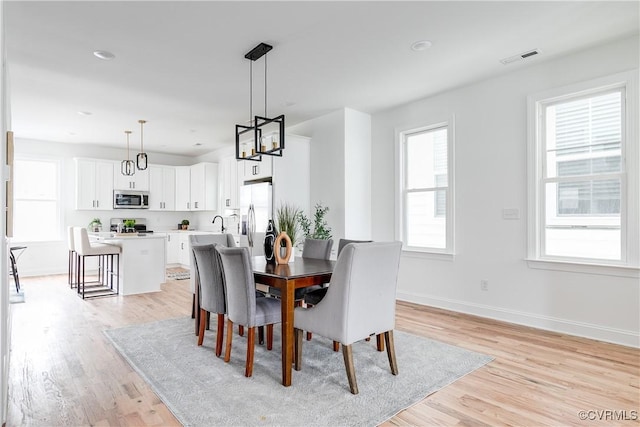 dining space with light wood-style flooring, visible vents, and baseboards